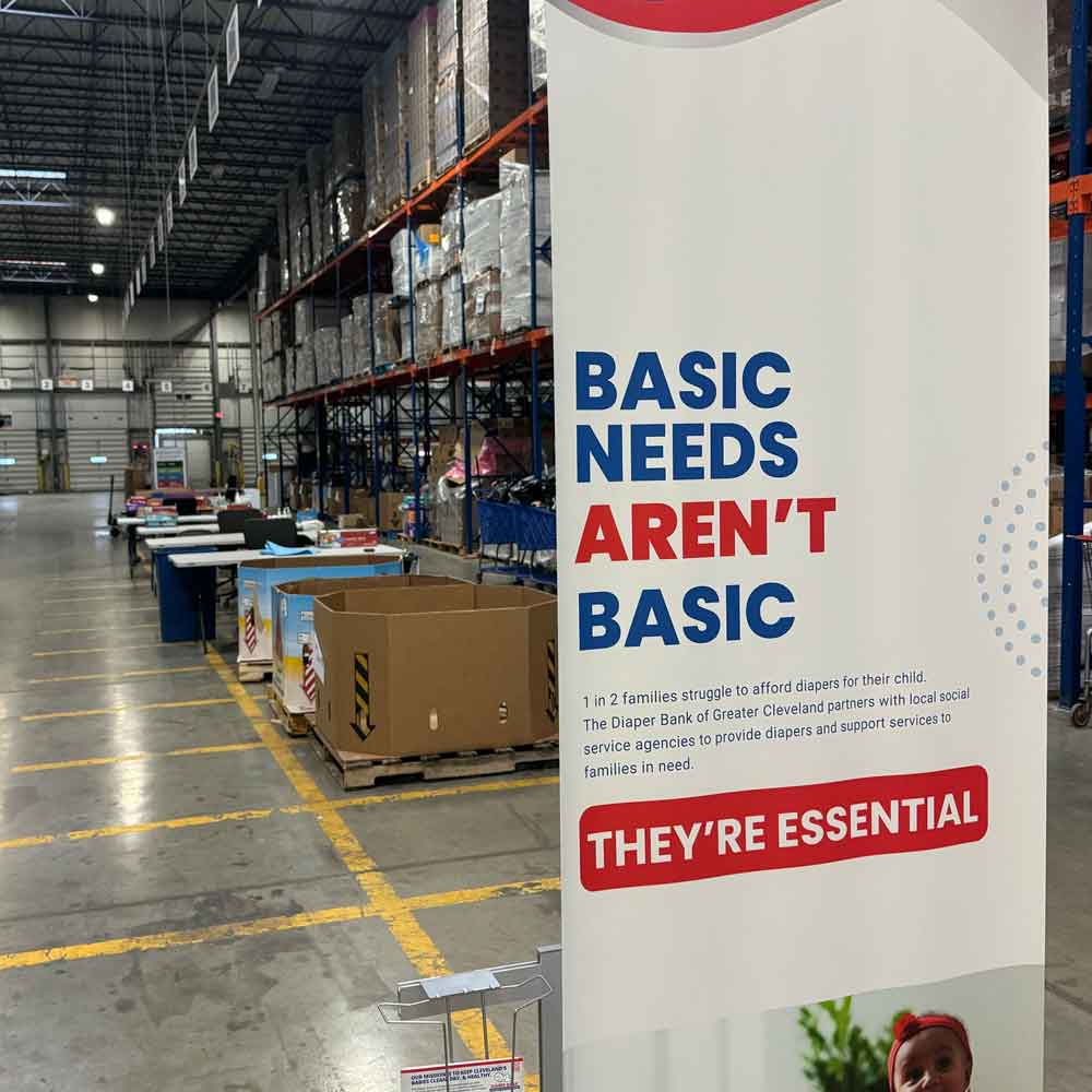Basic needs aren't basic banner stand in diaper bank warehouse.